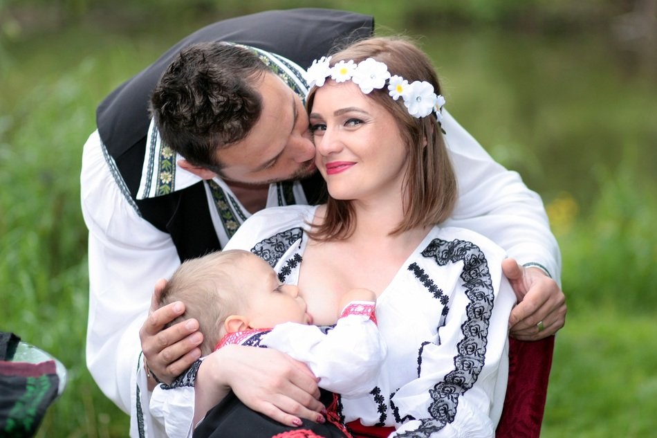 family in traditional costumes breastfeeding child