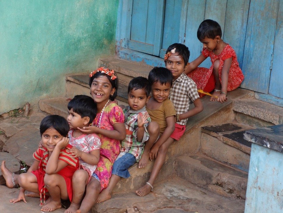 happy indian children are sitting on the stairs at the entrance to the house