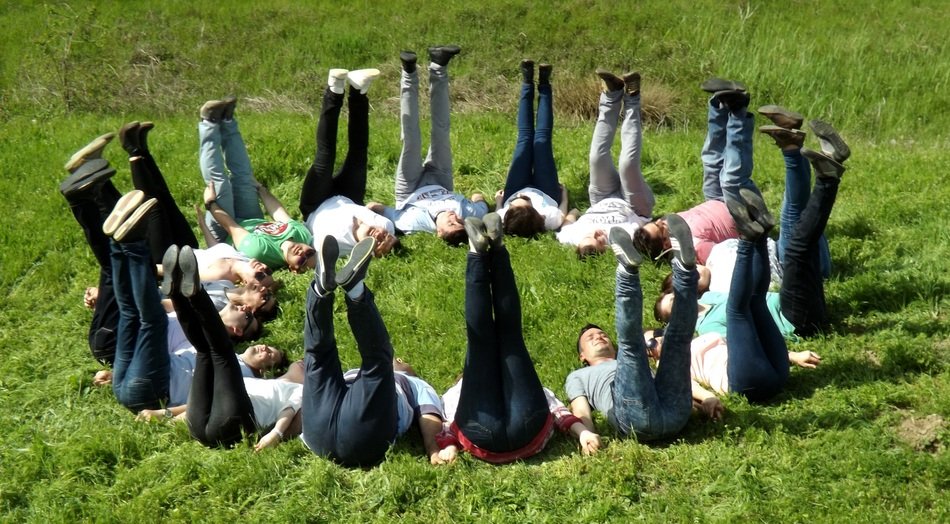 people in a circle with their legs raised on the grass