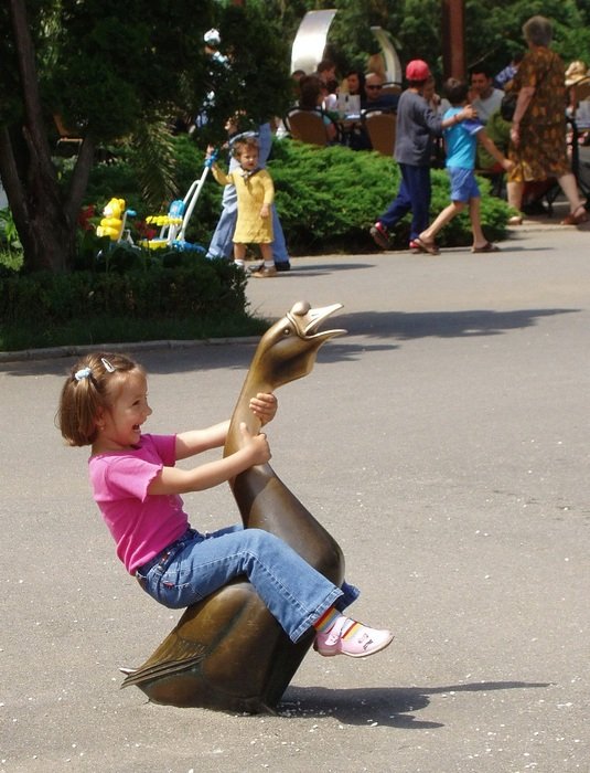 child sits on a goose statue