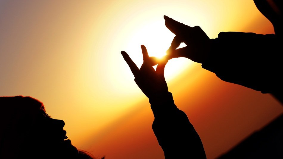 silhouettes of hands at sunset