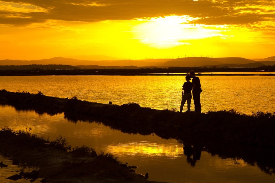 young couple on the shore of the pond at sunset
