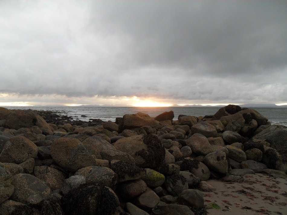 Rocks on the beach and sun on the horizon