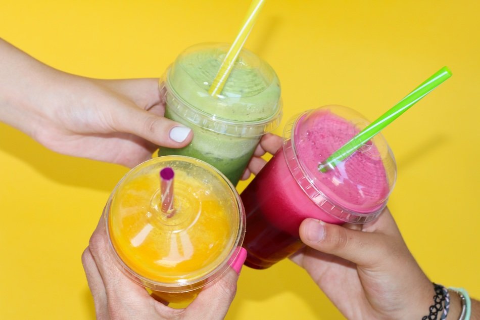 three cups of colorful Smoothies in hands