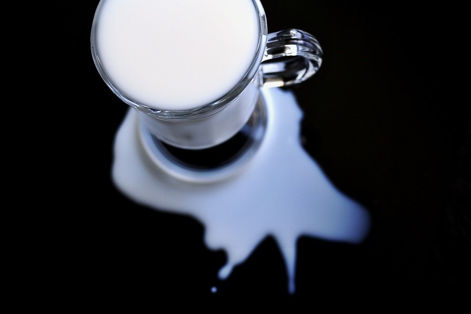 milk in glass and Spilt Milk on black background