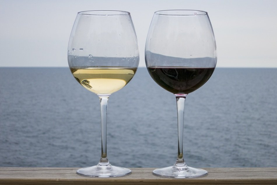 glass of red and white wine on the background of the sea coast