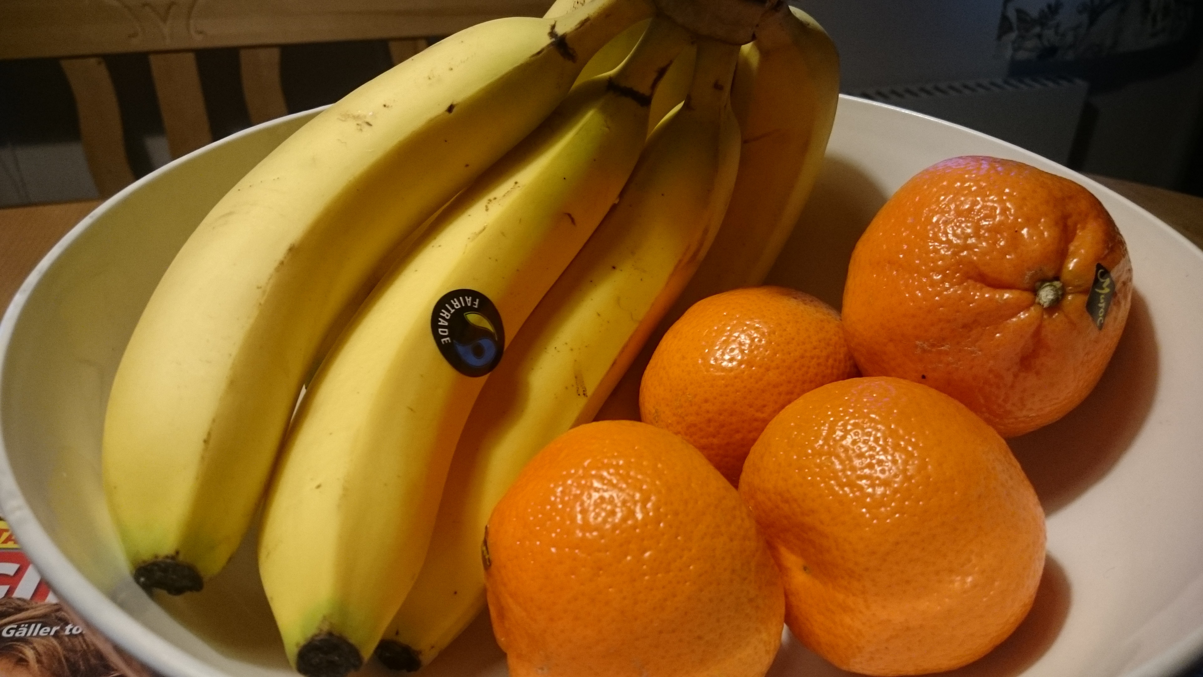 <b>Bananas</b> and orange tangerines on a white plate image.