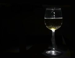 glass of white wine in a black background
