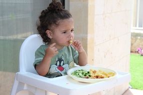 little girl eats at the table