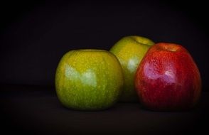 Green and red apples on the black background