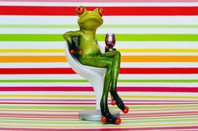 funny figurine of a frog on a chair with a glass