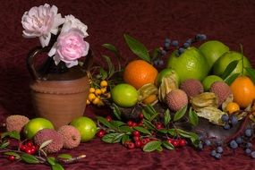 Still life with vegetables and fruits next to a pink rose