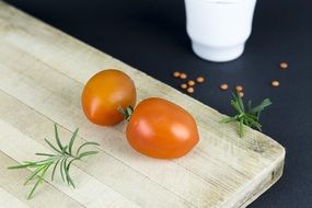 two tomatoes on a white wooden board