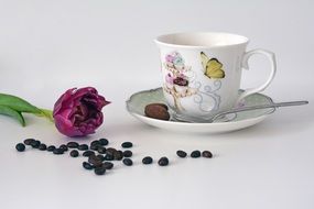 cup with coffee on a saucer next to a flower