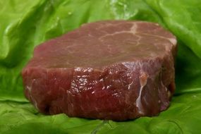 beef steak with blood on a green lettuce leaf