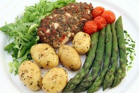 Asparagus, potato, salad, tomatoes and meat on plate