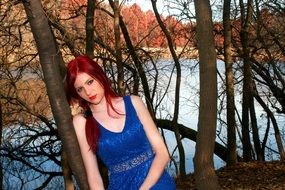 red-haired girl in a blue dress near the lake