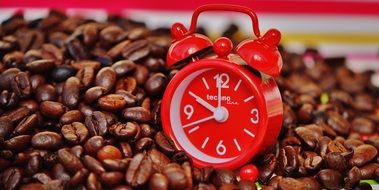 red alarm clock on coffee beans close up