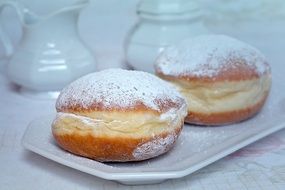 two donuts with powder on a white plate