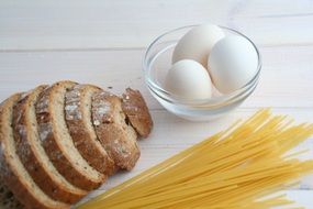 bread, pasta and eggs on a white table