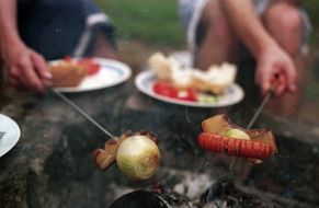 grilling bread, vegetables and sausages on the fire outside