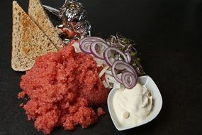 offal, red onion, toast and sauce on the table