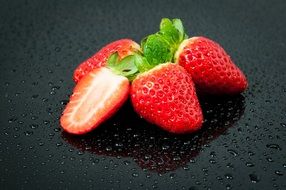 red strawberries on a black plate in drops