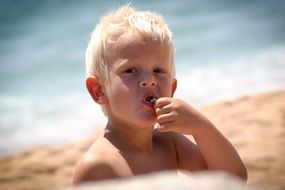 Child is eating something on the beach in Spain