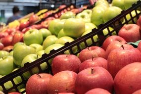 red and green apples on a shelf in a supermarket