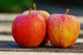 three red apples on the ground close-up