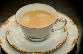 cup of coffee in gold trim dinnerware