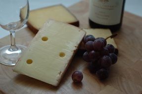 red cheese, grapes and red wine on a kitchen board