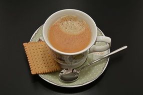 Coffee Cup with cracker on black desk