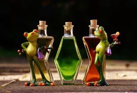 ceramic frogs on the background of multi-colored bottles with cocktails