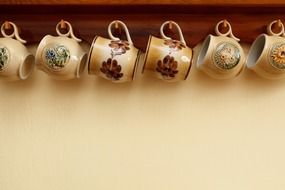 Ceramic coffee mugs hang in row