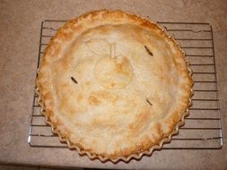 closed apple pie on a wire rack