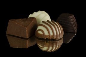 Four various chocolate candies on a dark background