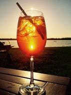 glass with cocktail on sunset background