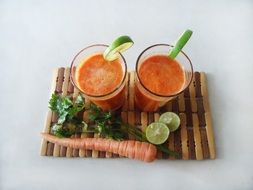two glasses with carrot juice and a slice of lime
