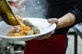 man pouring seafood to plate