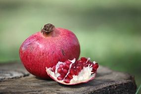 open Pomegranate Fruit on board at blurred green background