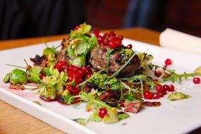 restaurant dish with meat and red berries