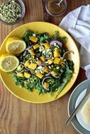 Salad with Mango, Lemons and green herbs on Table