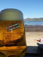 cold beer in a glass on the beach