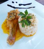 chicken leg with sauce and rice on a plate in a restaurant