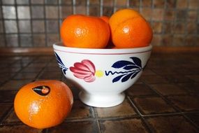 ripe tangerines in a cup with a pattern