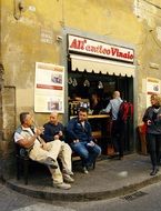 talking men sitting on street at wall of Restaurant, italy, florence