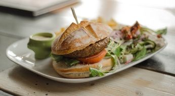 hamburger on a plate with green leaves close-up on blurred background