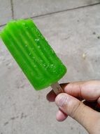 green Ice Candy on stick in hand