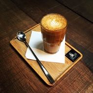 cup of latte on a wooden board with a spoon